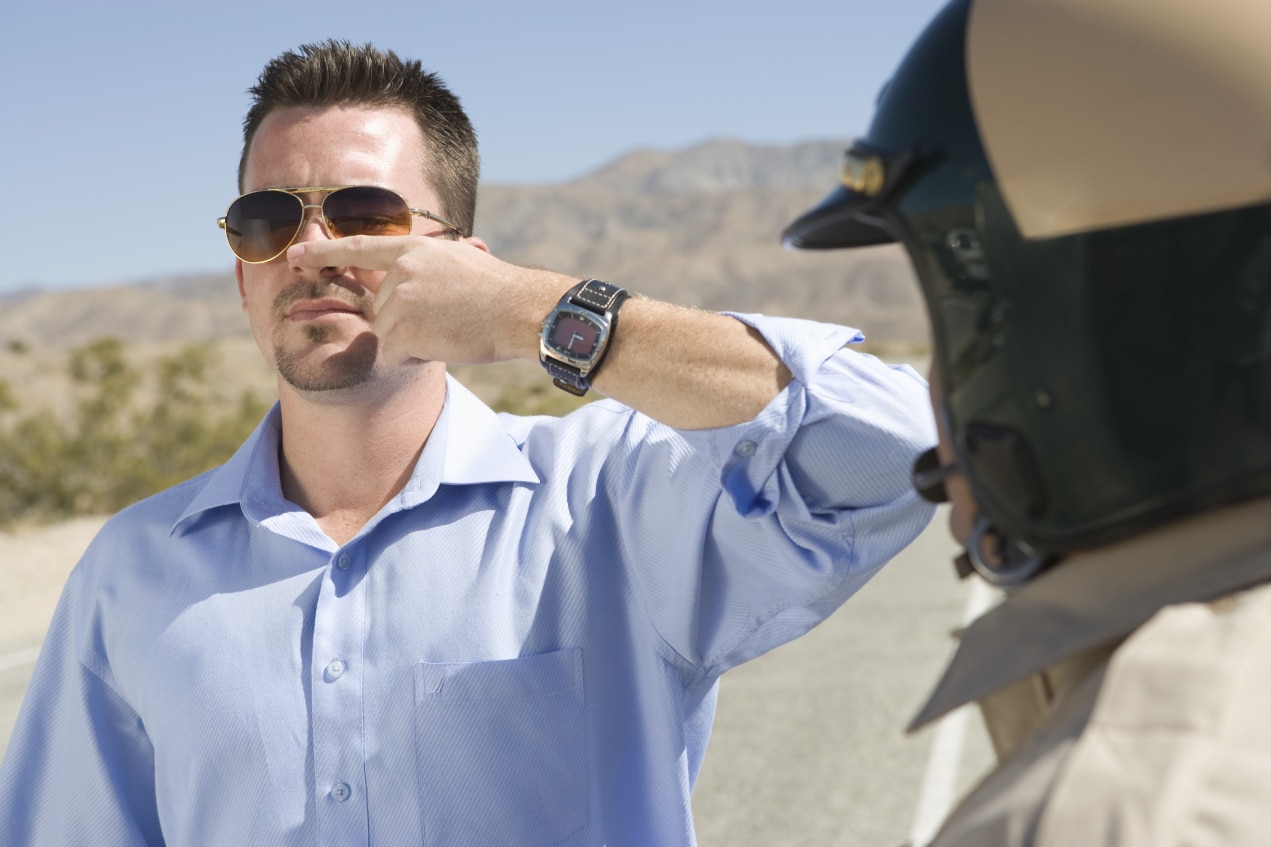 Young man touches nose with eyes closed at the request of a police officer during a suspected DWI stop.